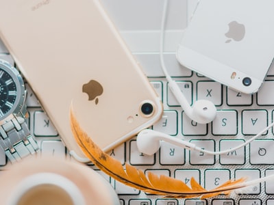 黄金iPhone 7旁边白色的苹果EarPods和银iPhone 5 s
